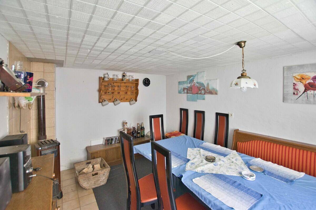 Geräumiger Essbereich mit großem Tisch, Sitzbank und traditionellem Kachelofen.