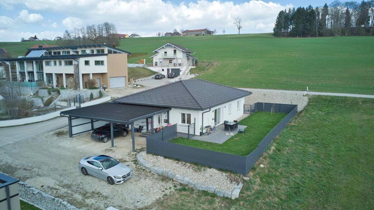 Drohnenaufnahme eines modernen Einfamilienhauses mit Carport, Garten und Terrasse in ländlicher Umgebung.