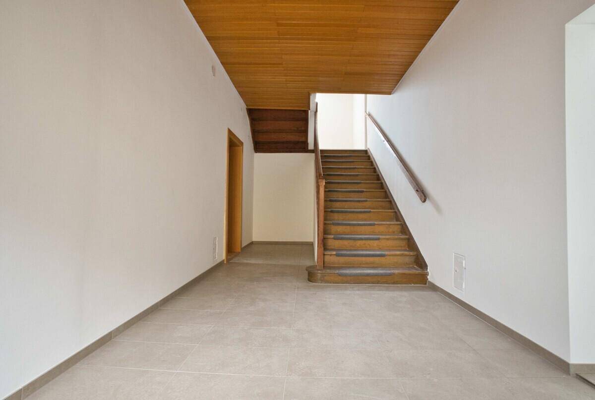 Geräumiger Eingangsbereich mit Holztreppe und Fliesenboden, der zu den oberen Etagen führt.