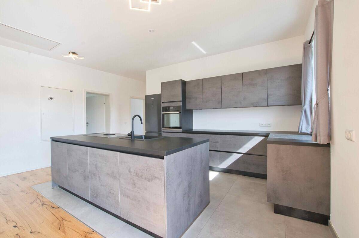 Voll ausgestattete moderne Küche mit grauen Fronten, Backofen und großem Kühlschrank.