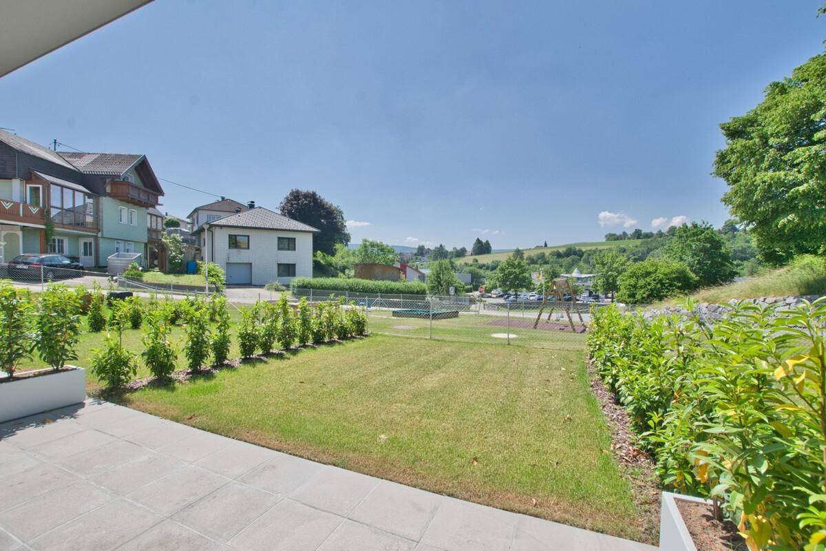 Blick von der Terrasse auf den Rasen, Spielplatz und die weite Landschaft.