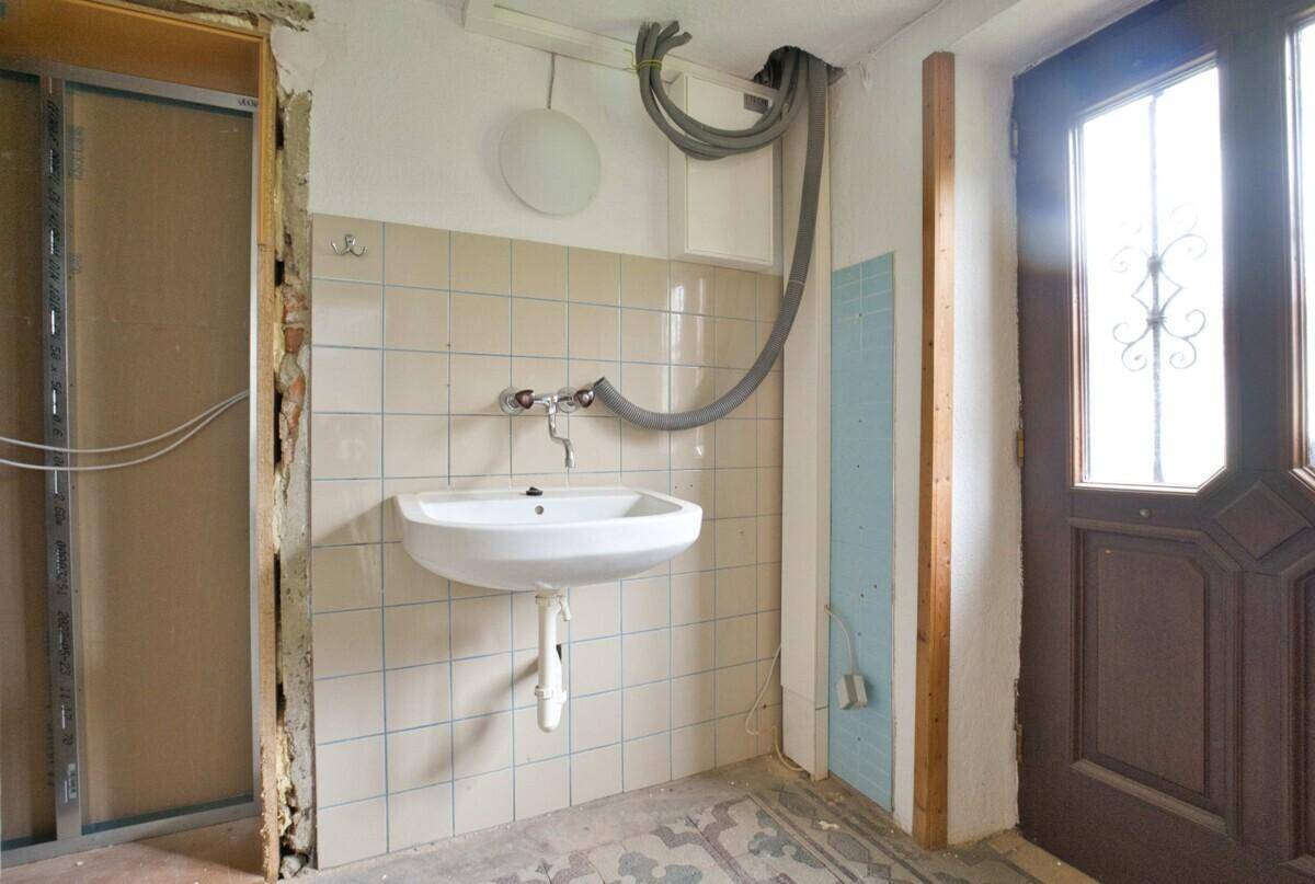 Kleiner Raum mit Waschbecken und Fliesen, der sich in Renovierung befindet.
