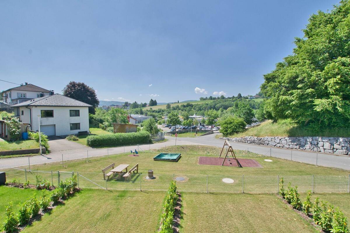 Blick vom Grundstück auf einen Spielplatz, umliegende Häuser und die grüne Landschaft.