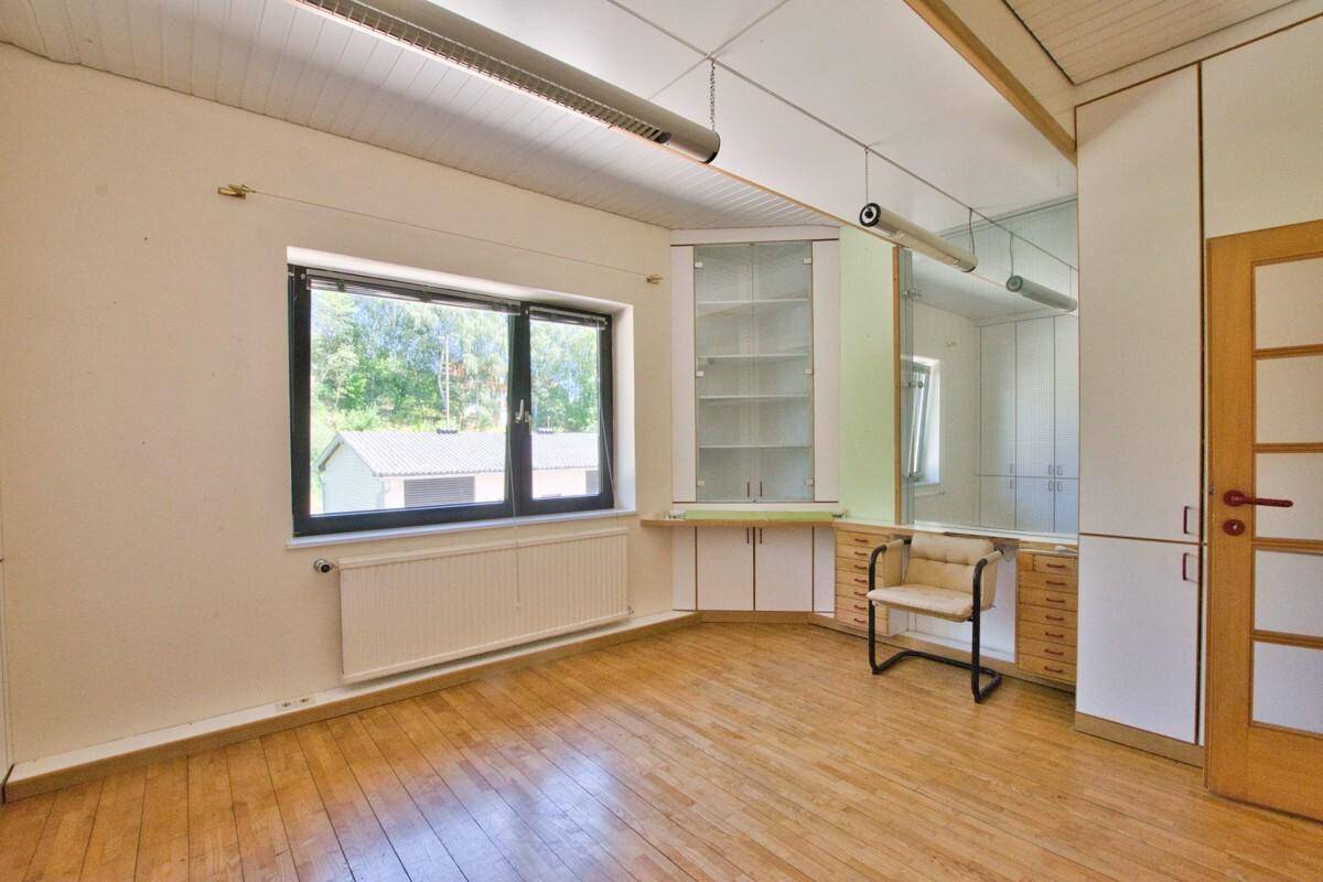 Geräumiges Büro mit maßgefertigten Schränken, Holzfußboden und viel Tageslicht.