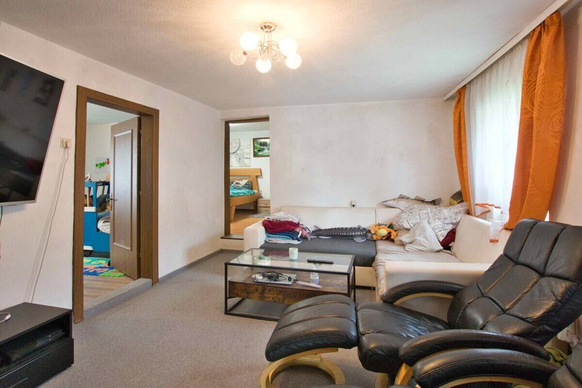Gemütliches Wohnzimmer mit Sofa, Fernseher und Teppichboden.