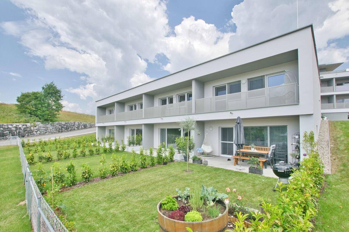 Moderne Wohnanlage mit gepflegtem Garten, Terrasse und Sitzgelegenheiten im Freien.