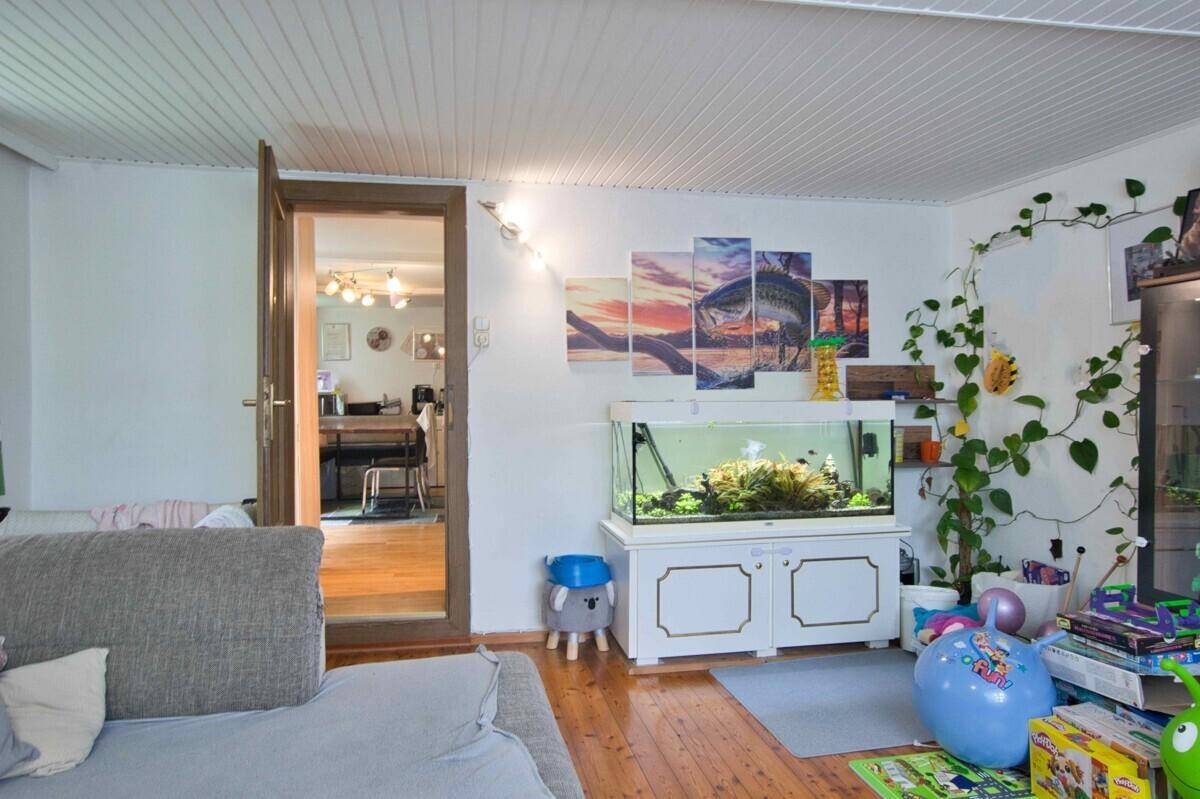 Wohnzimmer mit Aquarium, Holzfußboden und Blick in den angrenzenden Essbereich.