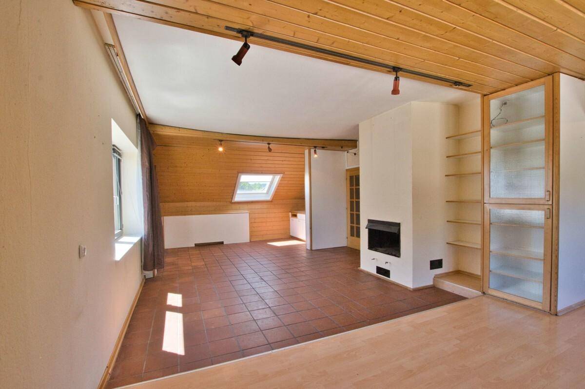 Geräumiges Wohnzimmer mit Holzbalkendecke, Terrakottafliesen und integriertem Kamin.