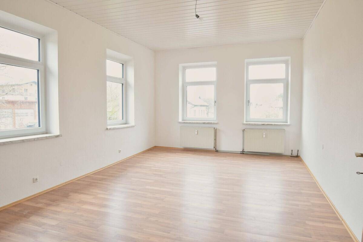 Großes, helles Zimmer mit Laminatboden und vielen Fenstern, bietet vielseitige Nutzungsmöglichkeiten.