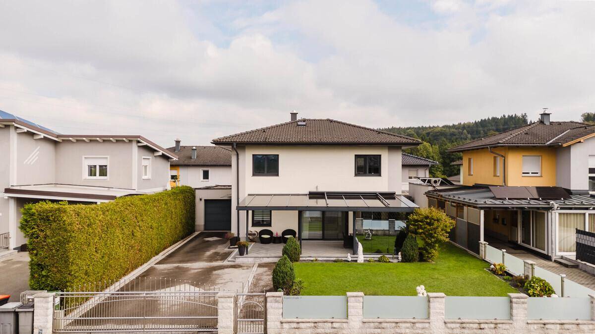 Ansicht des Einfamilienhauses von vorne mit gepflegtem Garten, Hecke und Zaun.
