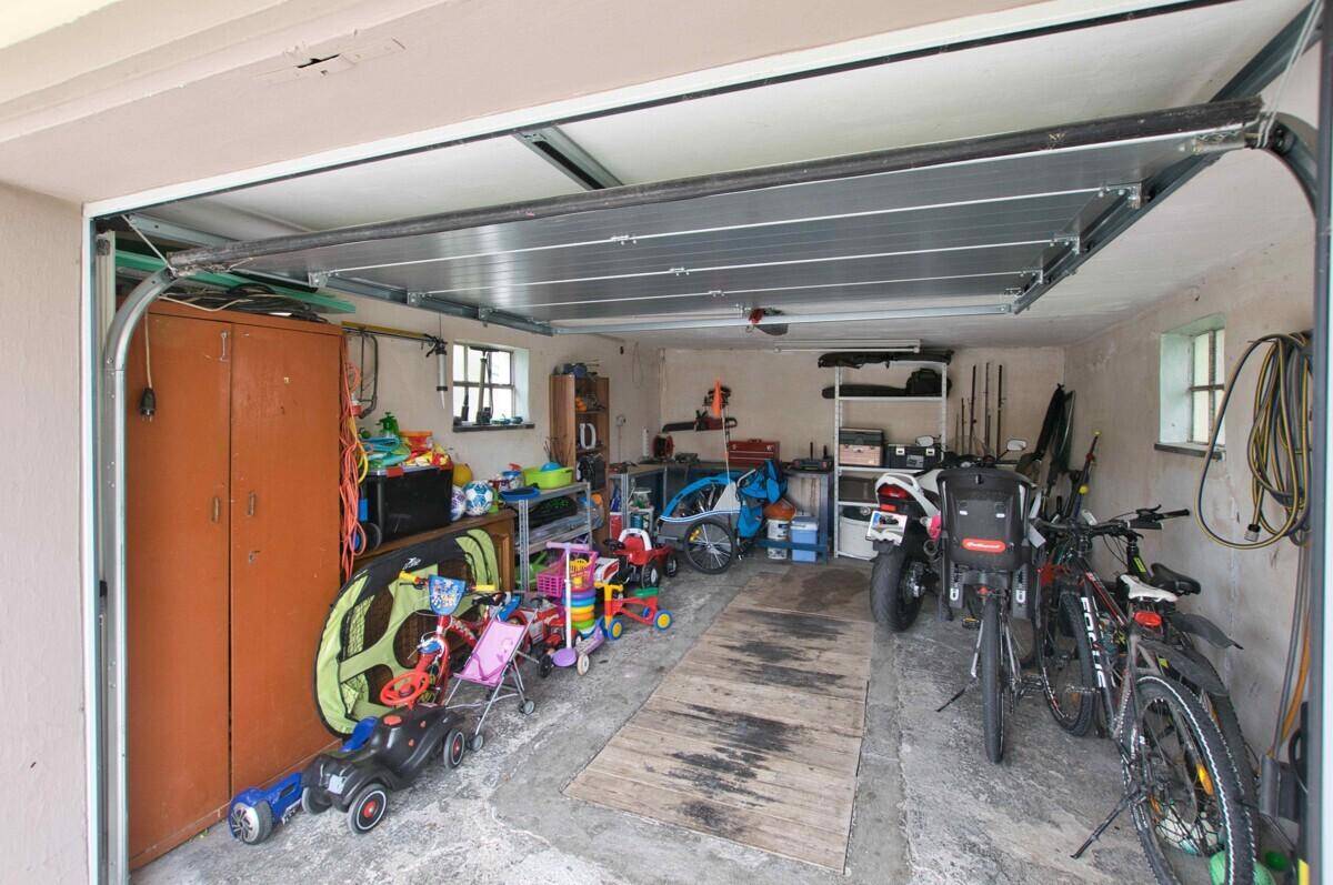 Geräumige Garage mit geöffnetem Tor, Fahrrädern und Lagerfläche.