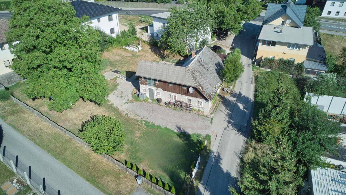Klare Luftaufnahme eines älteren Hauses mit Satteldach und großem Garten in ländlicher Umgebung.