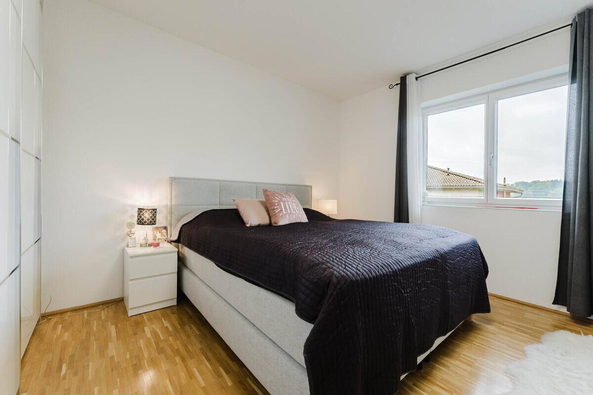 Gemütliches Schlafzimmer mit Doppelbett, Holzboden und großem Fenster für viel Licht.