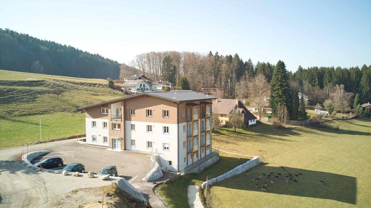 Luftaufnahme eines modernen Mehrfamilienhauses in ländlicher Umgebung mit viel Grün.