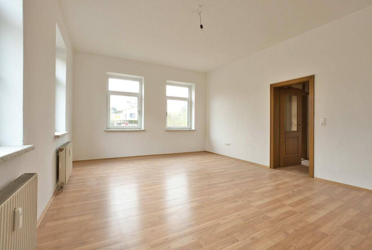 Geräumiges, helles Zimmer mit Laminatboden und Holztür, bereit zur individuellen Gestaltung.