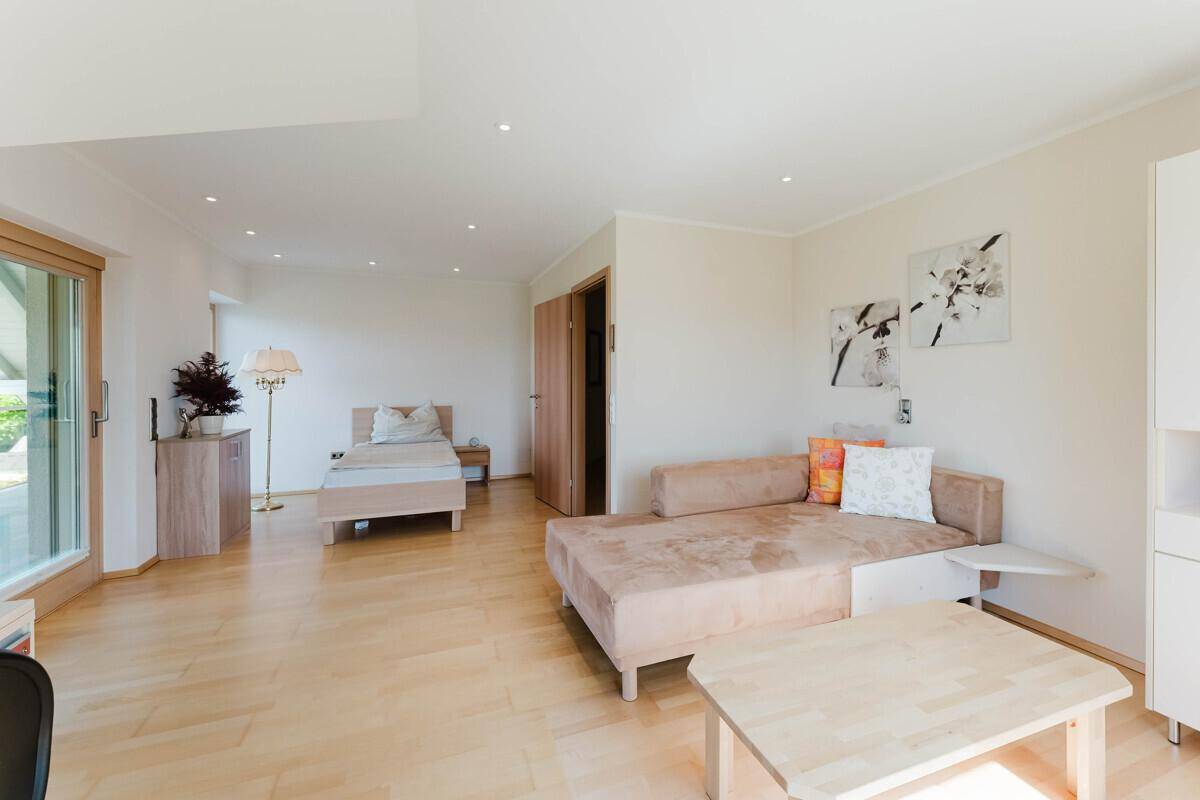 Vielseitiger Raum im Dachgeschoss mit Holzboden, Tageslicht und gemütlicher Einrichtung.
