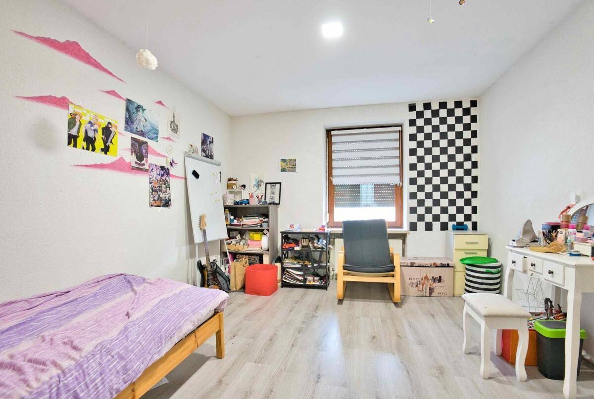 Jugendzimmer mit hellem Laminatboden und kreativer Wandgestaltung, ideal für Kinder oder Teenager.