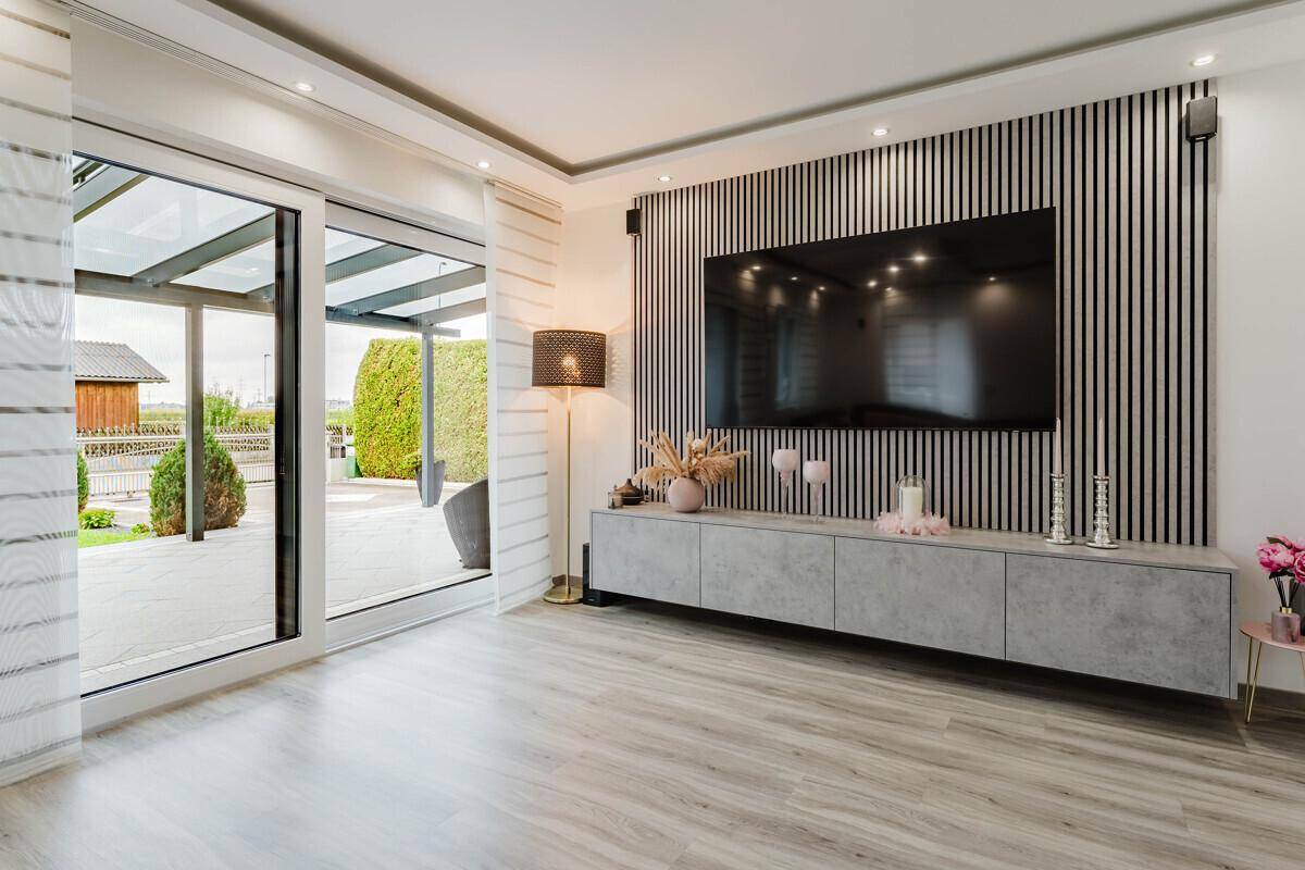 Moderner Wohnbereich mit großem Fernseher, stilvoller Wandgestaltung und Terrassenzugang.