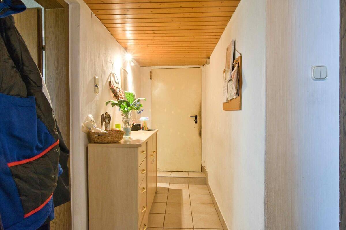 Schmaler Flur mit Kommode, Holzdecke und Zugang zu weiteren Räumen.