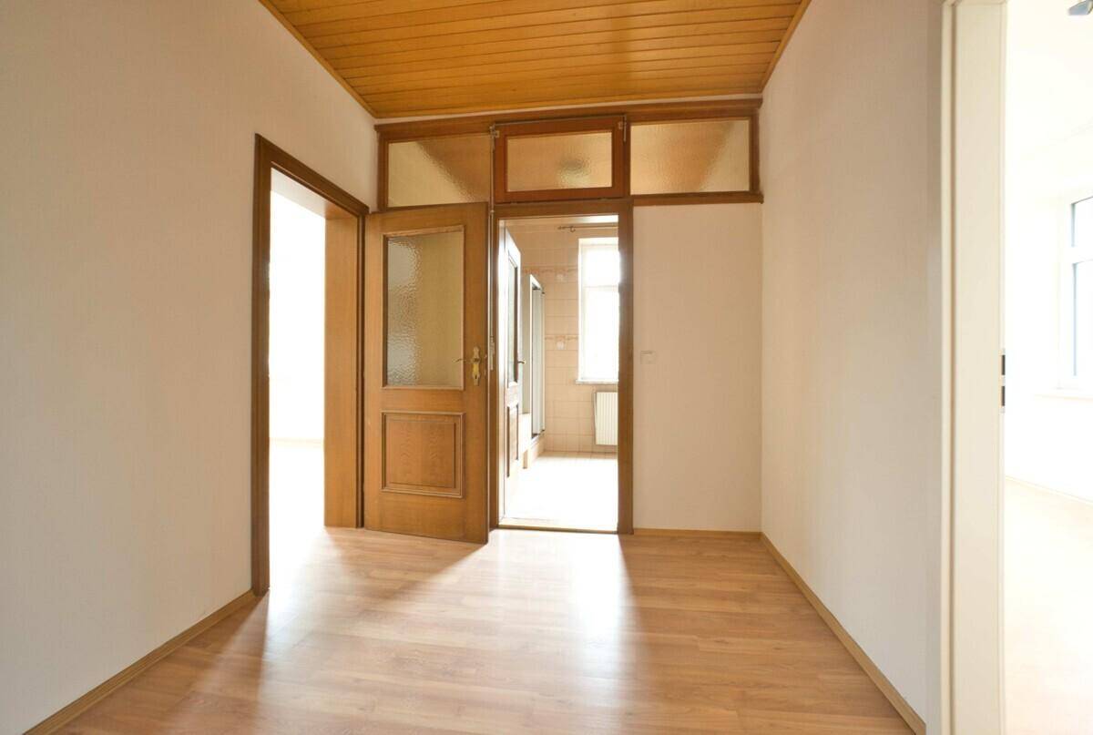 Flur mit Holztüren, Holzdecke und Laminatboden, der zu weiteren Räumen führt.
