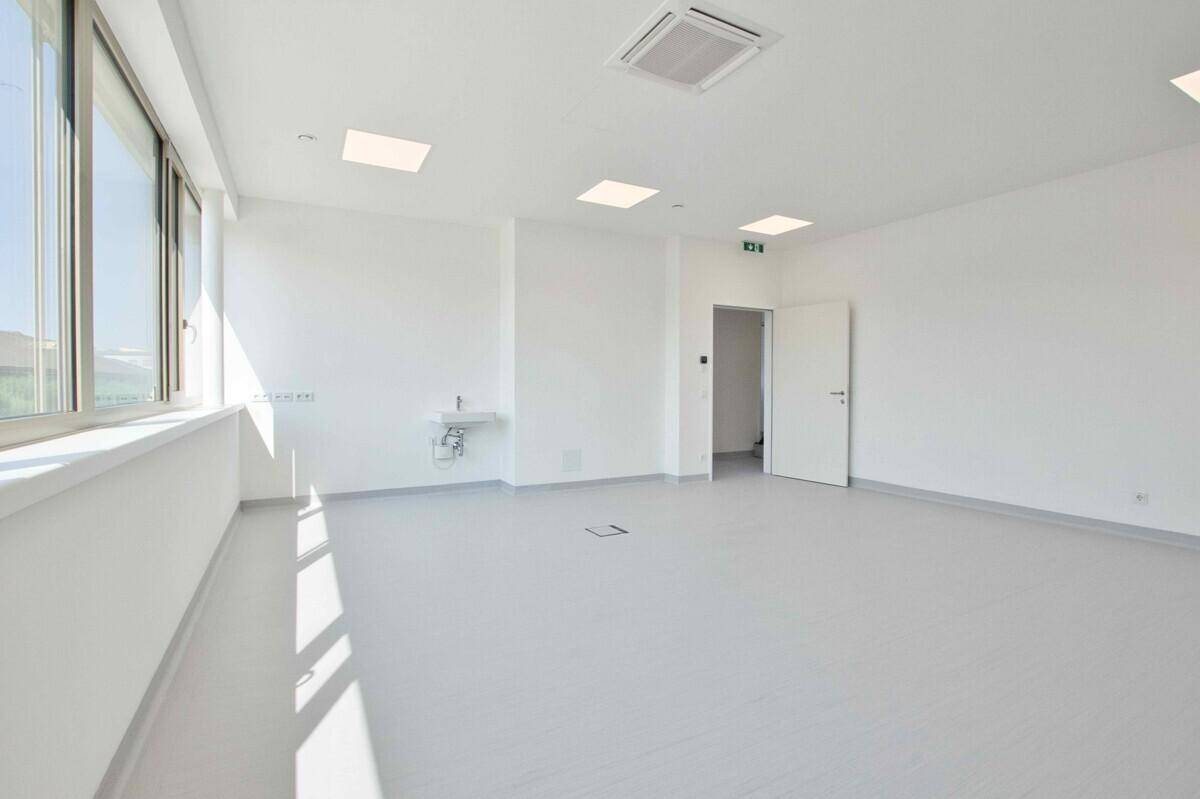 Heller, leerer Raum mit Waschbecken und Zugang zu weiteren Bereichen, vielseitig nutzbar.