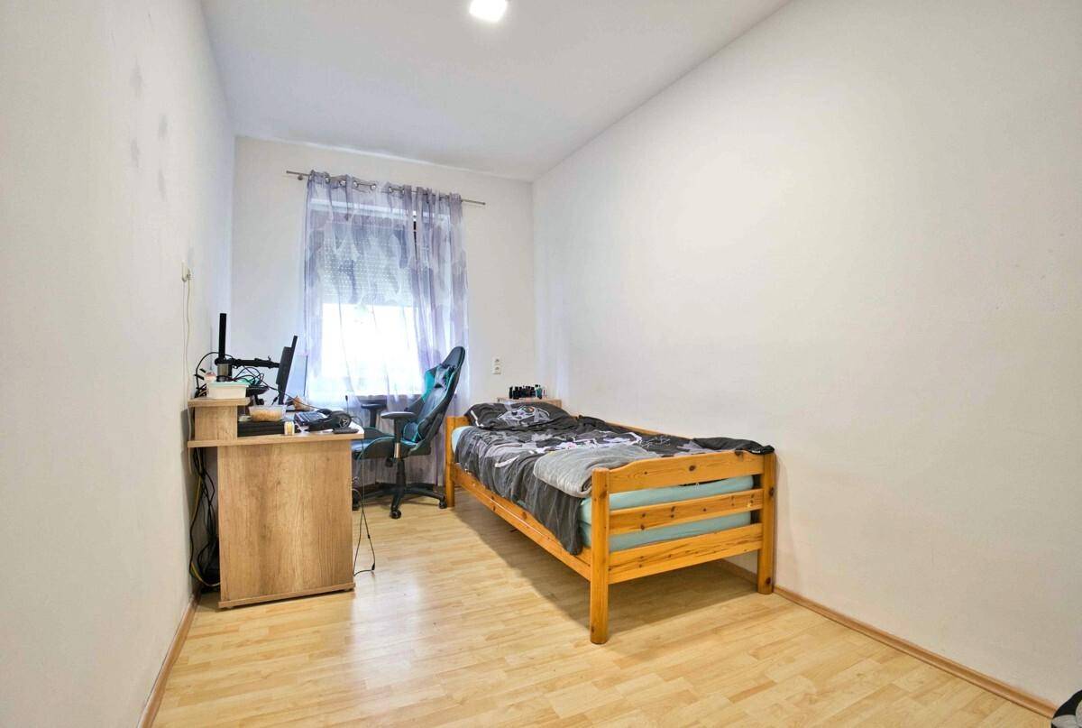 Jugendzimmer mit Einzelbett, Schreibtisch und hellem Laminatboden, ideal für Studierende oder Gäste.