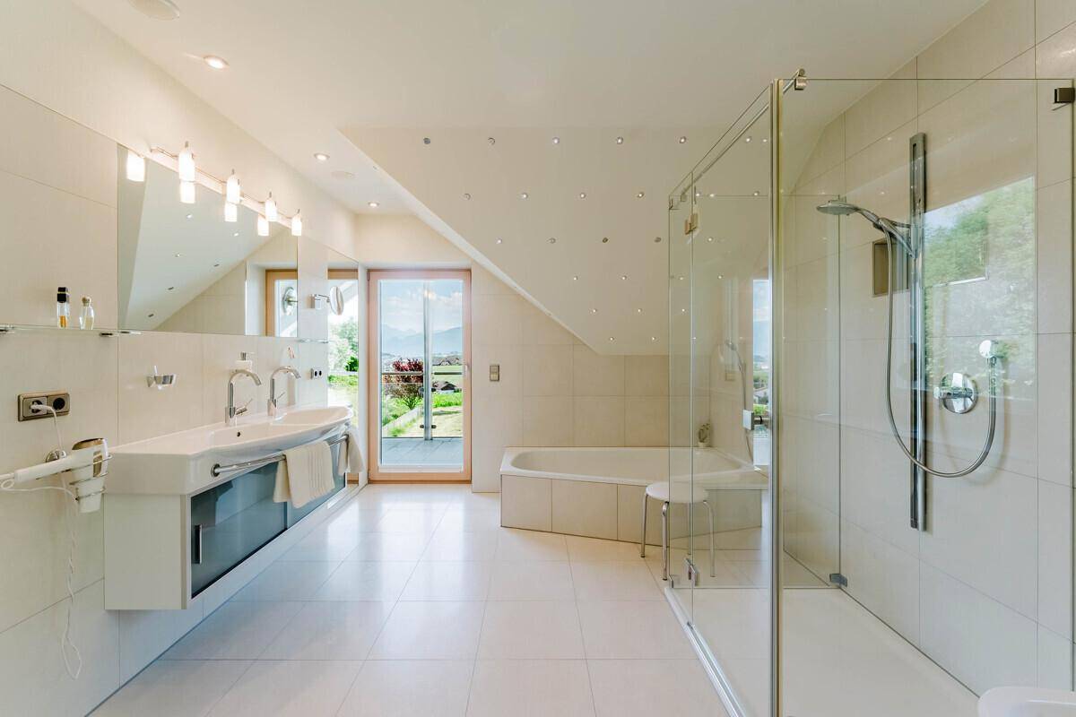 Modernes Badezimmer mit Doppelwaschbecken, großer Dusche, Badewanne und Bergblick.