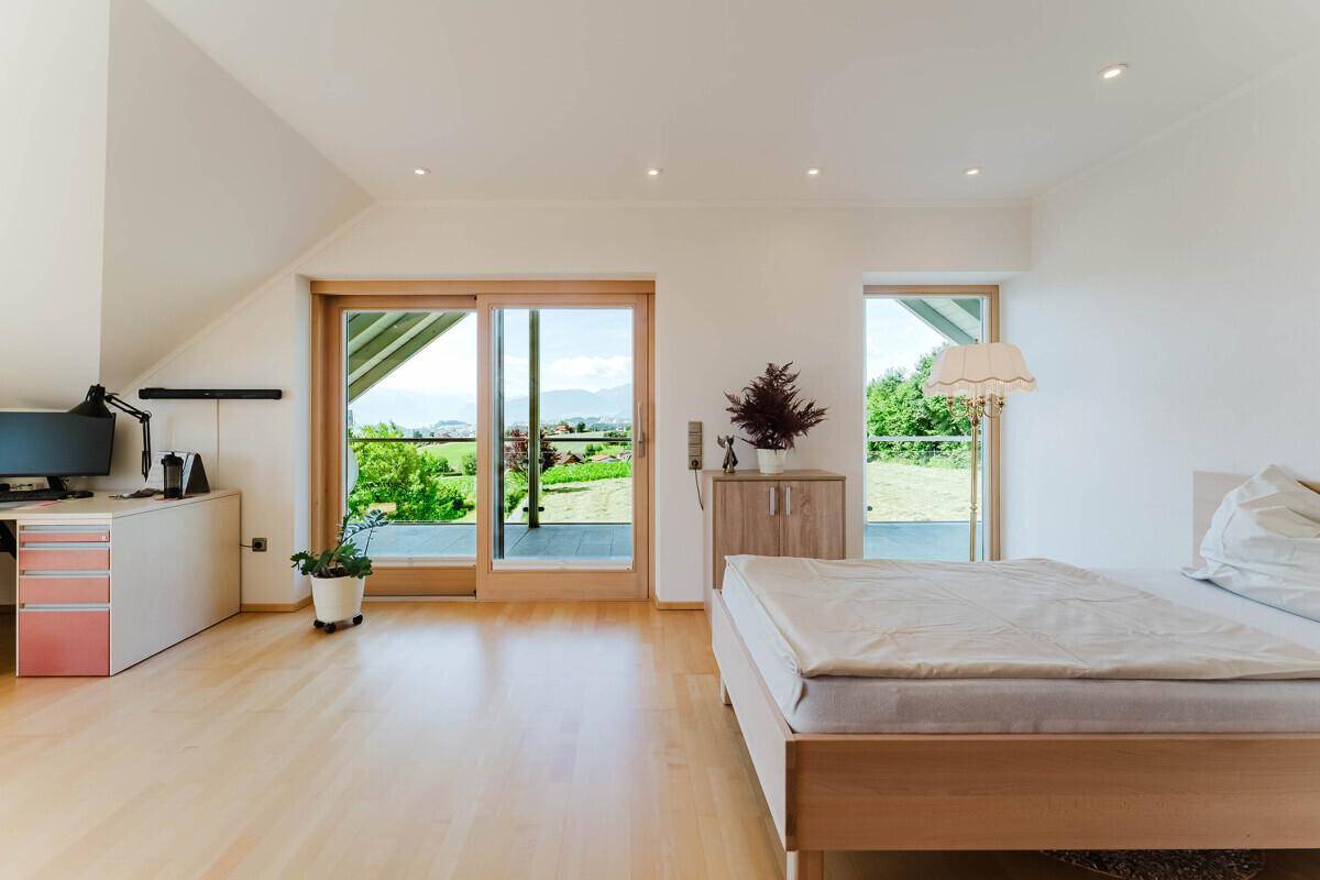 Helles Schlafzimmer mit Arbeitsbereich, Holzboden und direktem Zugang zum Balkon.