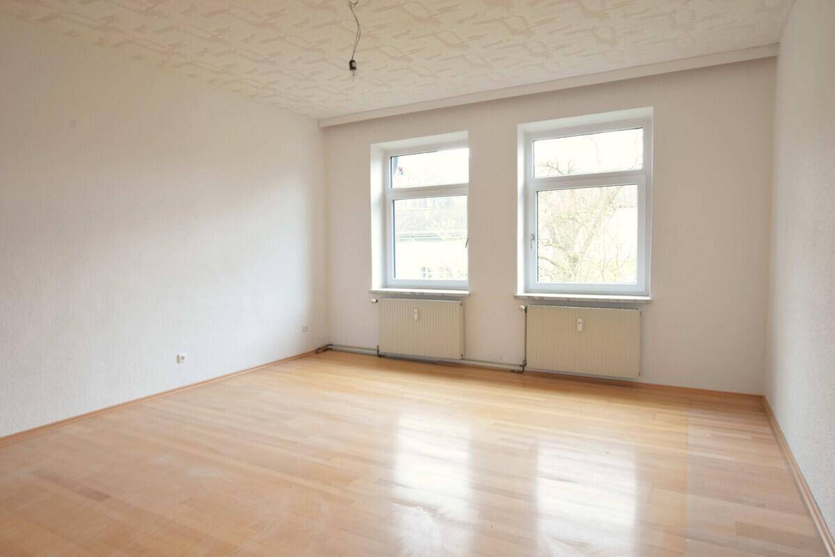 Helles Schlafzimmer mit Laminatboden und zwei Fenstern, bietet eine ruhige Rückzugsmöglichkeit.