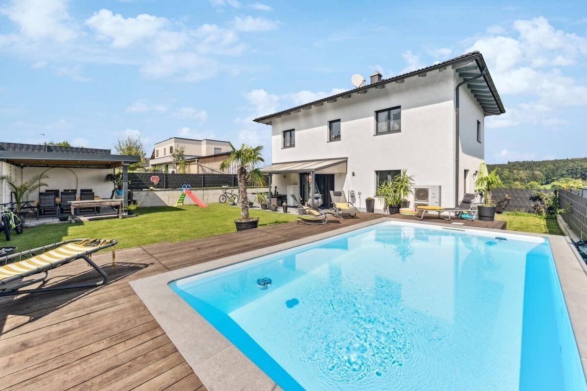Modernes Einfamilienhaus mit großem Garten, Pool und Holzdeck für entspannte Sommertage.