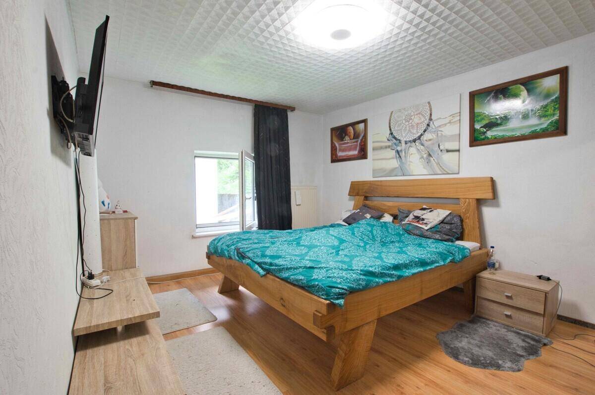 Schlafzimmer mit rustikalem Holzdoppelbett, Fenster und hellem Laminatboden.