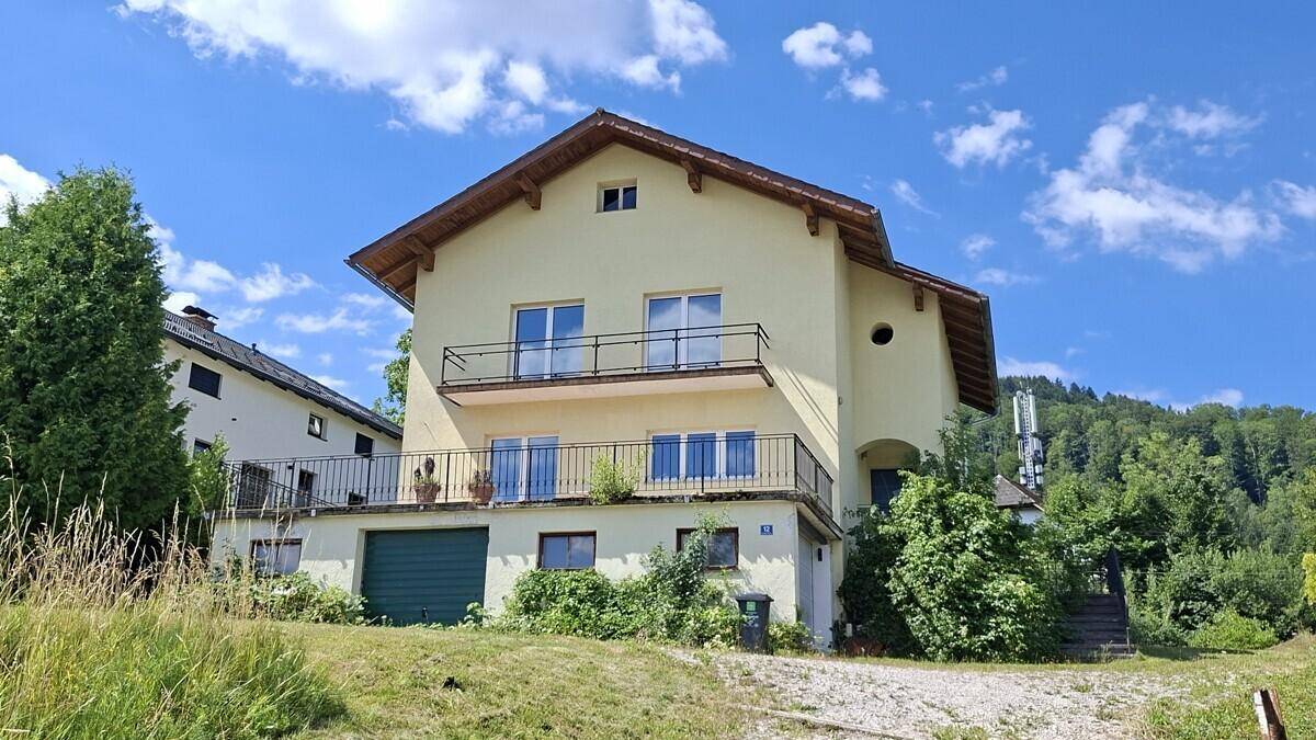 Freistehendes Haus mit mehreren Balkonen, Garage und Gartenbereich in sonniger Lage.