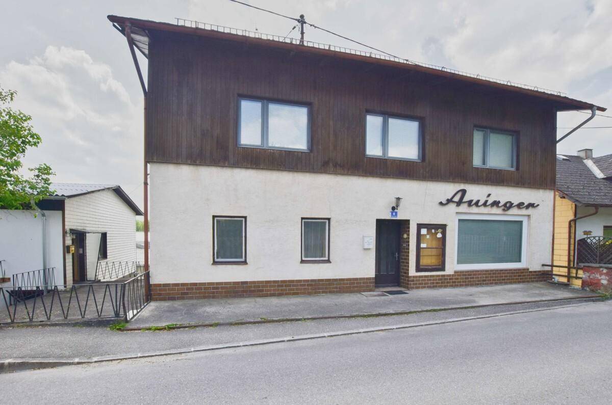 Vorderansicht des Gebäudes mit Geschäftseingang und Fenstern im Obergeschoss.