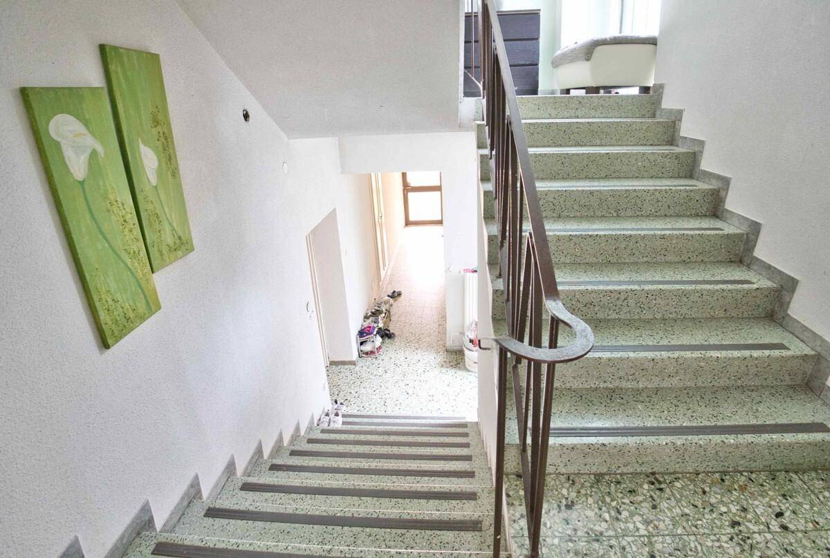 Treppenhaus mit Terrazzoboden und Metallgeländer, das die Stockwerke des Hauses verbindet.