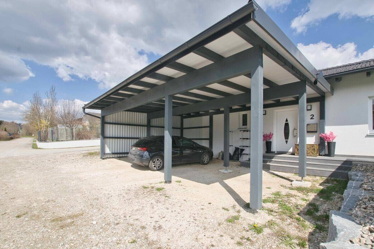 Eingangsbereich des Hauses mit modernem Carport und Stellplatz für ein Fahrzeug.