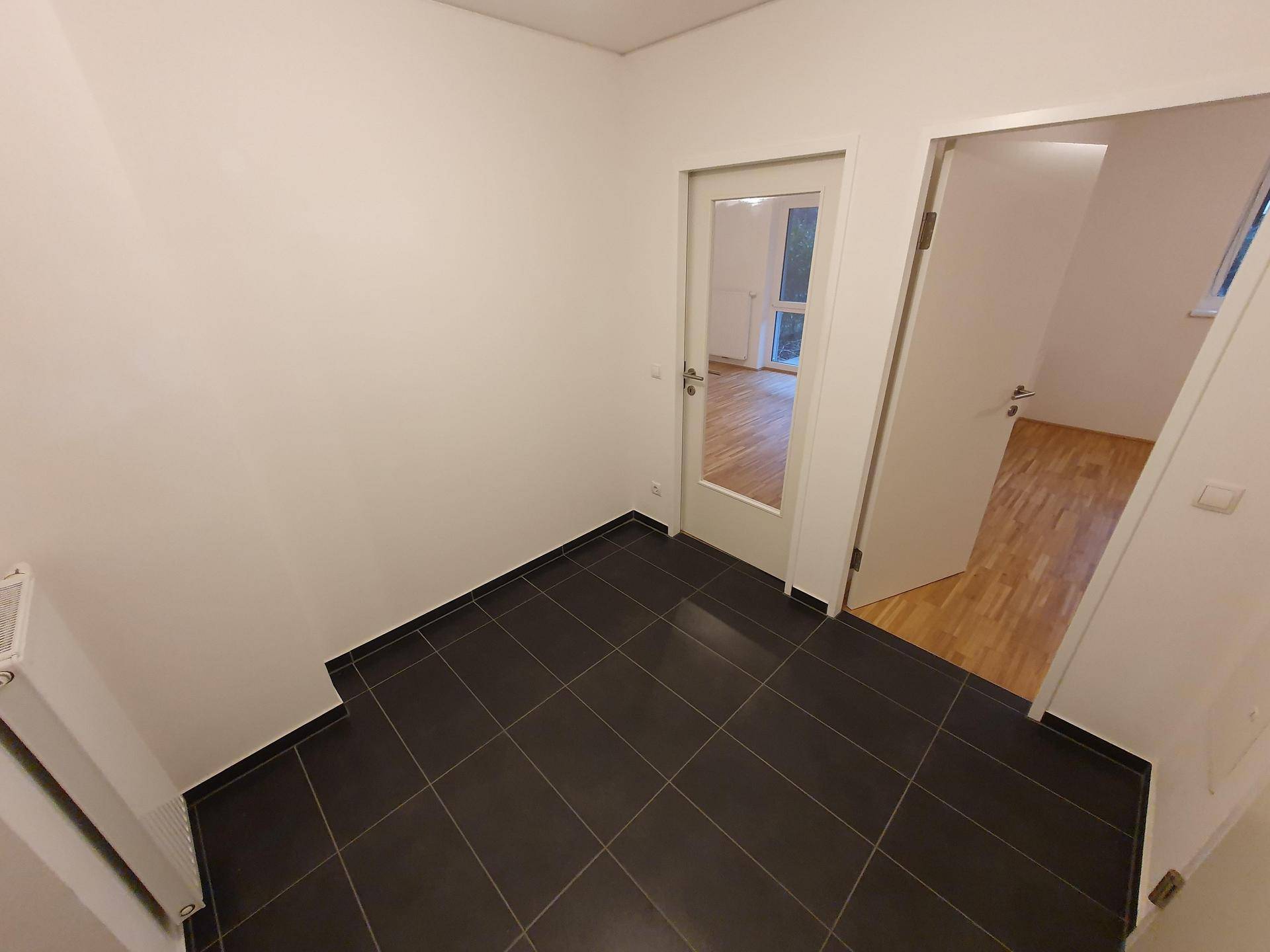 Eingangsbereich mit dunklen Fliesen und Zugang zu weiteren Räumen der Wohnung.