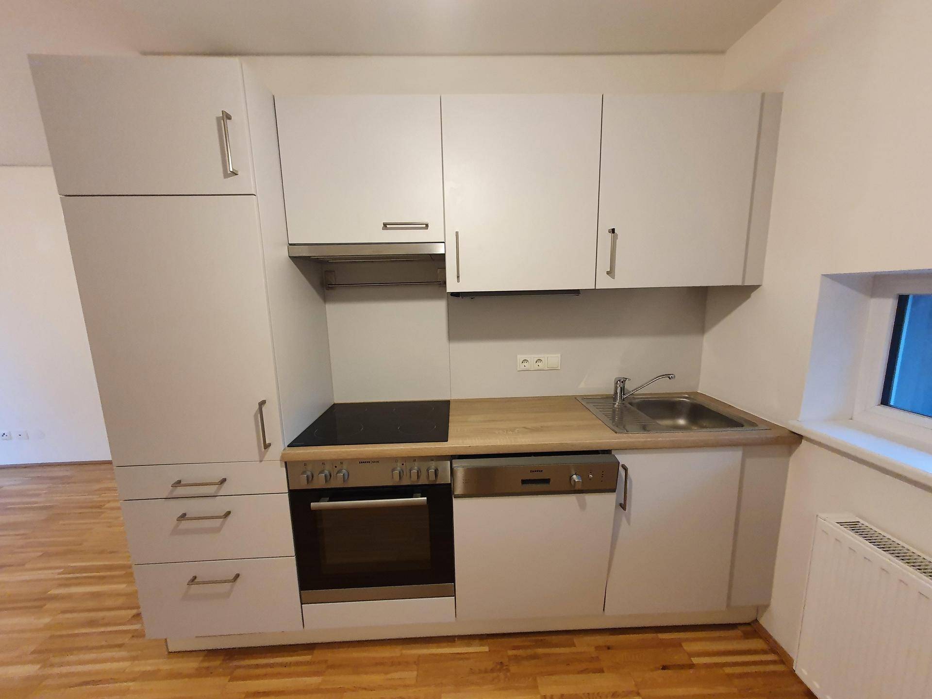 Kompakte Einbauküche mit hellen Fronten, Holz-Arbeitsplatte und modernen Geräten.