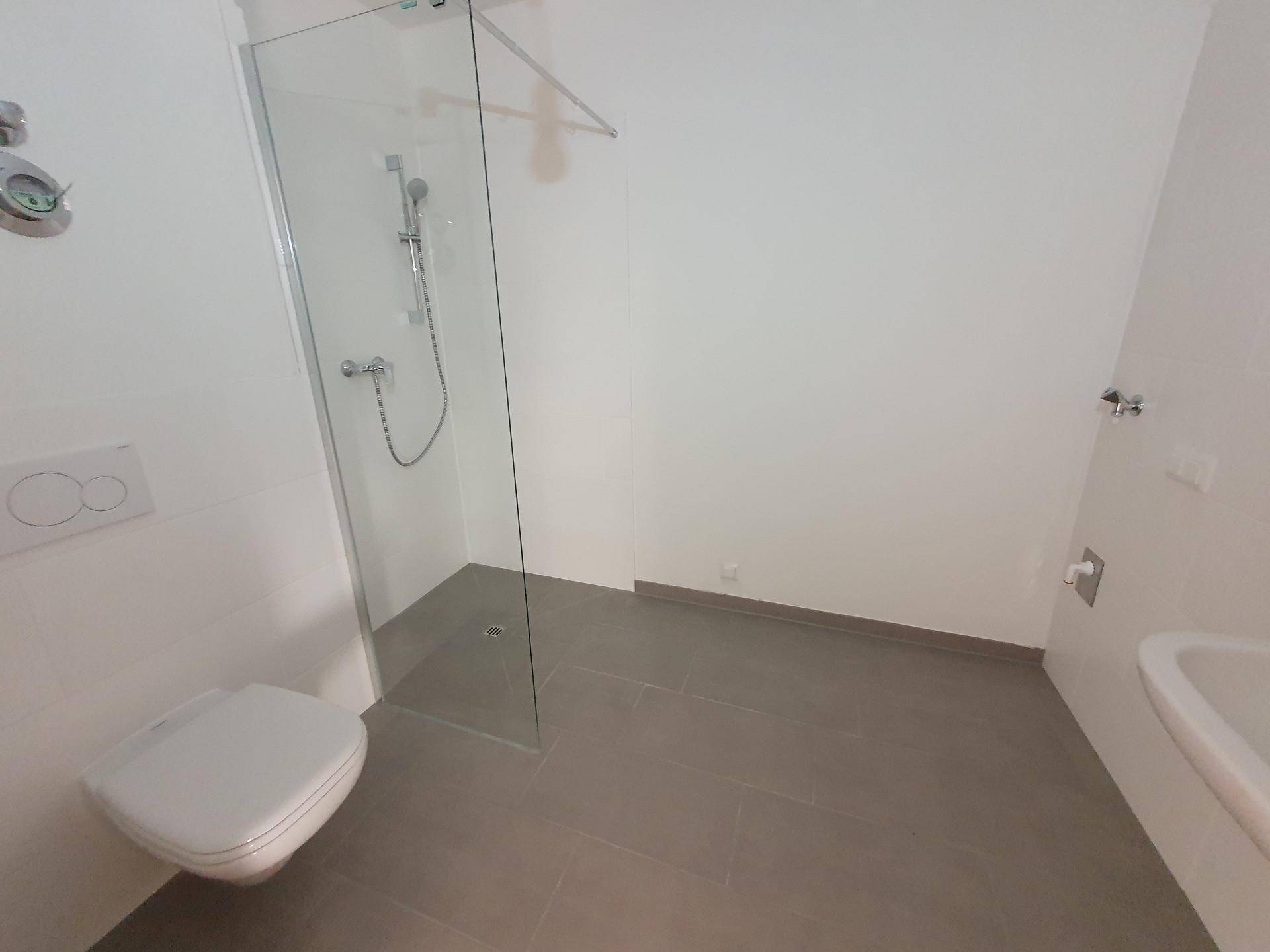 Helles Badezimmer mit wandhängendem WC, ebenerdiger Dusche und modernen Fliesen.