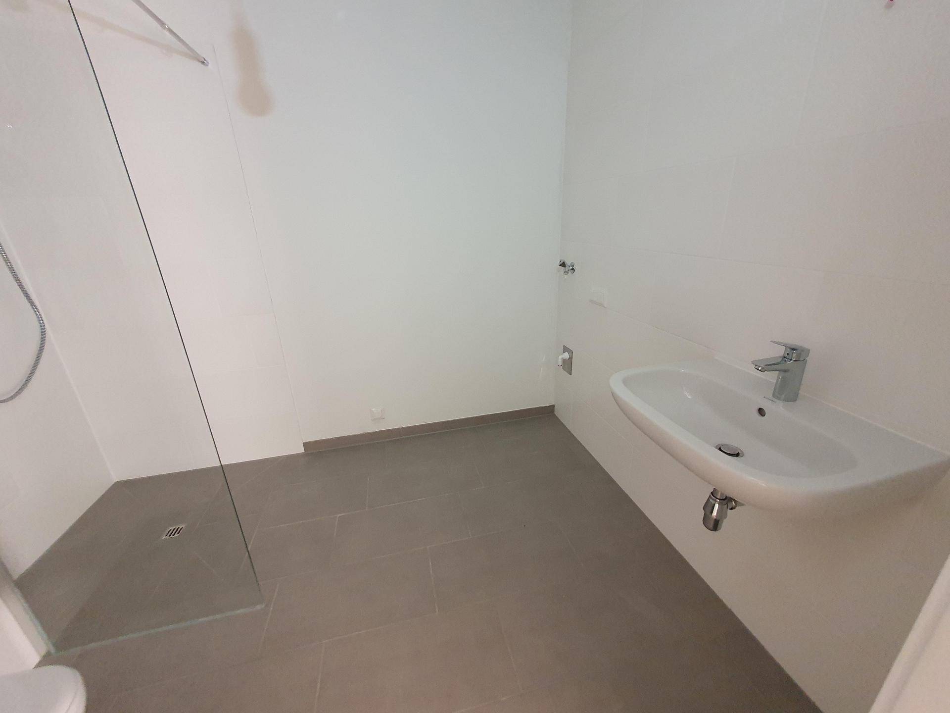 Modernes Badezimmer mit ebenerdiger Dusche, Waschbecken und grauen Fliesen.