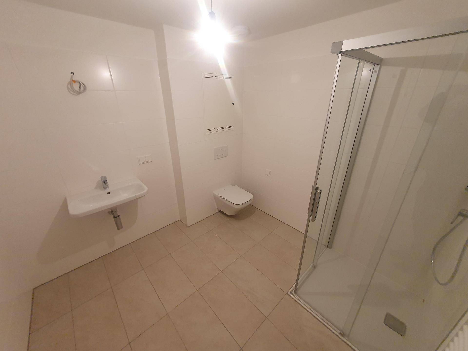 Modernes Badezimmer mit Duschkabine, Waschbecken und wandhängendem WC.
