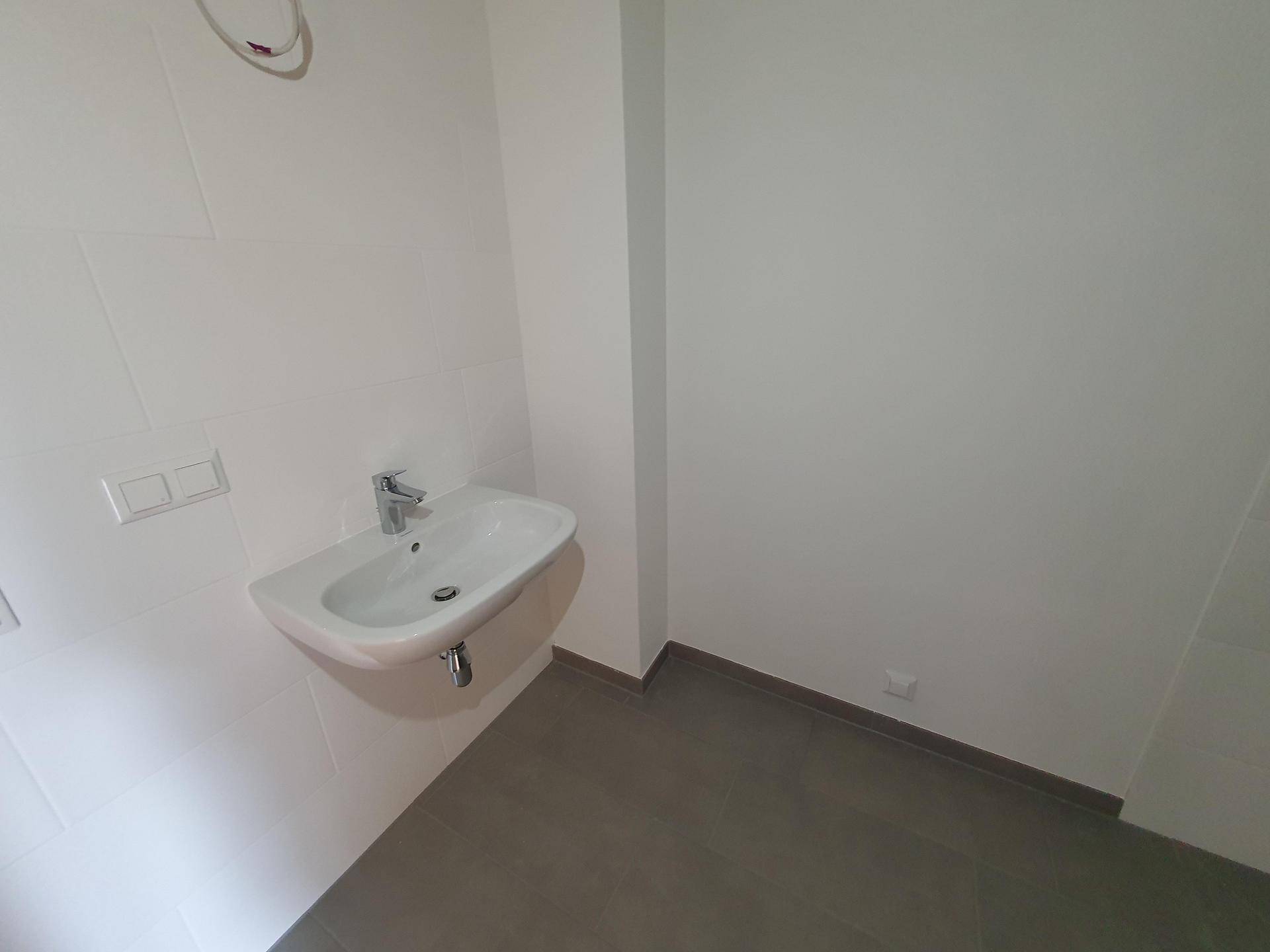 Modernes Gäste-WC mit wandhängendem Waschbecken und hellen Fliesen an Wänden und Boden.