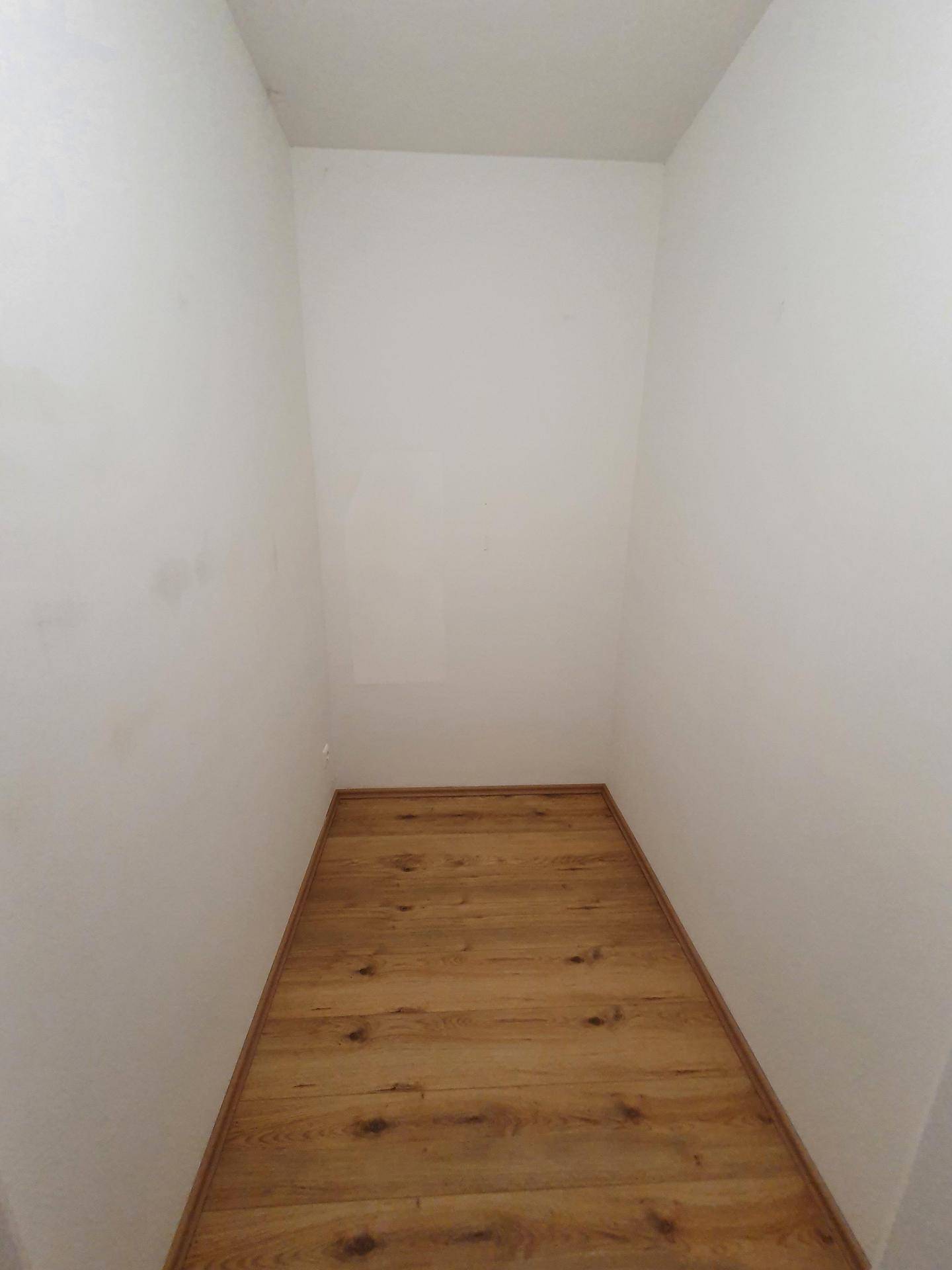 Praktischer Abstellraum mit Laminatboden und weißen Wänden für zusätzlichen Stauraum.