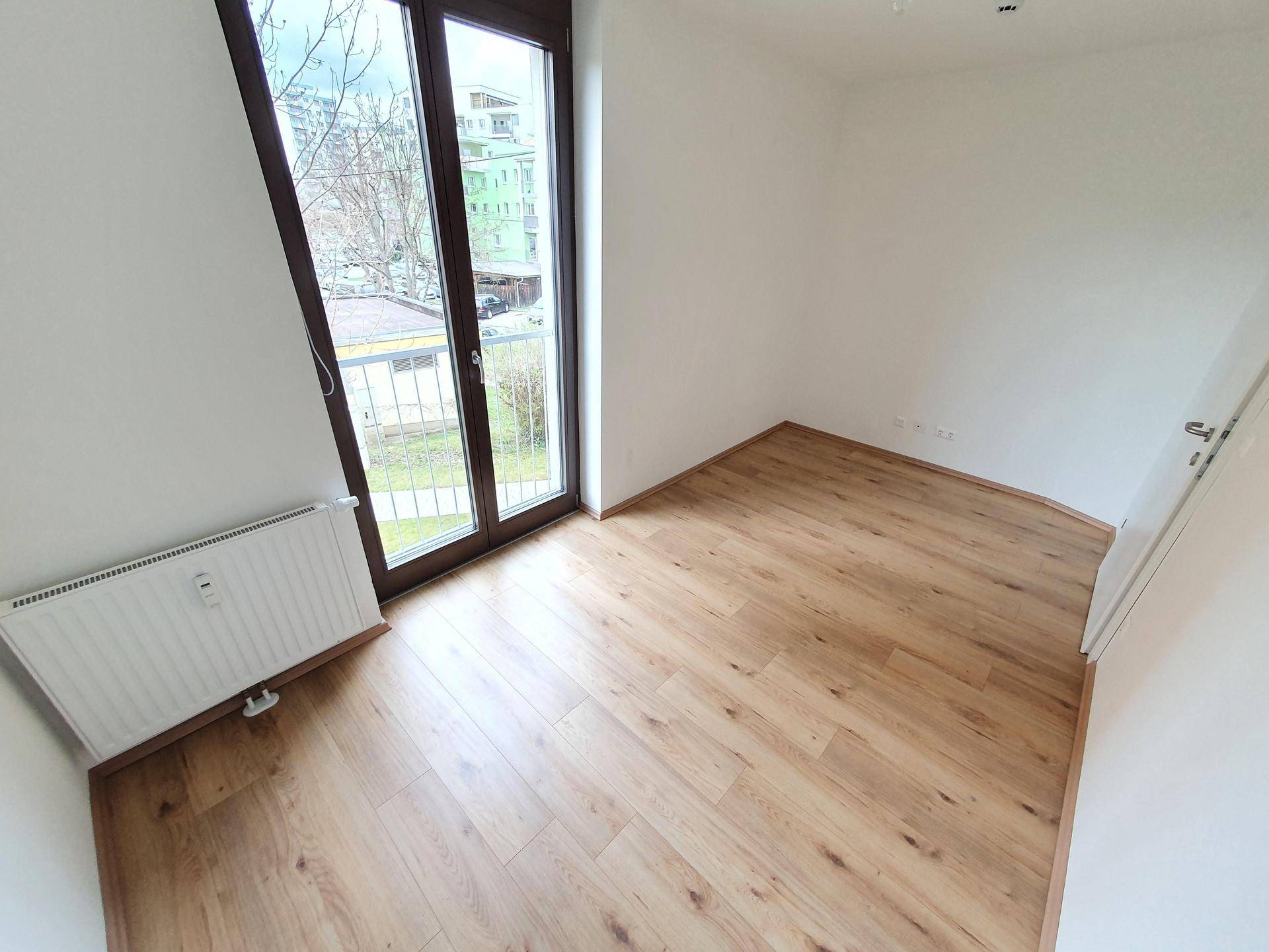 Heller Raum mit Laminatboden und großem Fenster, das viel Tageslicht bietet.