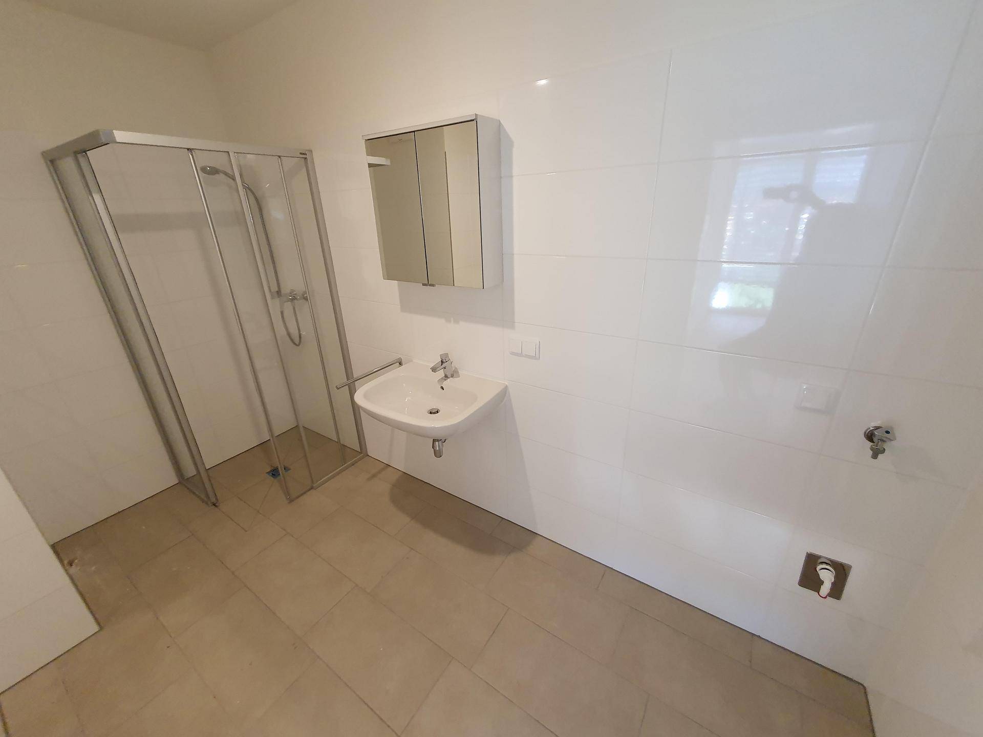 Modernes Badezimmer mit Dusche, Waschbecken, Spiegelschrank und weißen Fliesen an den Wänden.