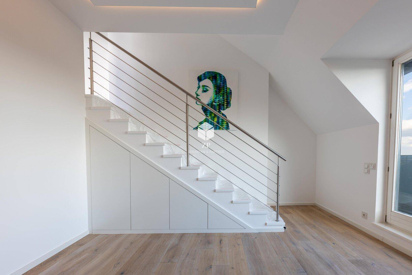 Moderne Treppe mit Edelstahlgeländer und integriertem Stauraum unter der Dachschräge.