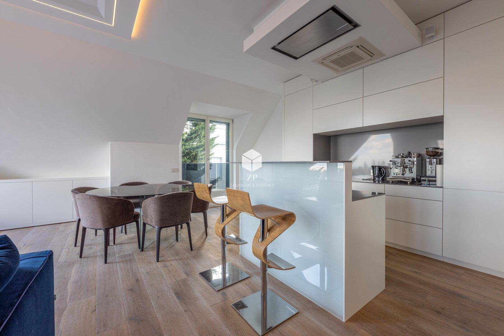 Offener Wohnbereich mit moderner Küche, Essbereich und Zugang zu einem Balkon.