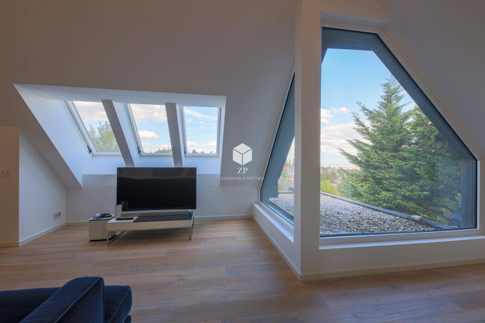 Lichtdurchfluteter Wohnbereich mit einzigartigen Fensterformen und Panoramablick ins Grüne.