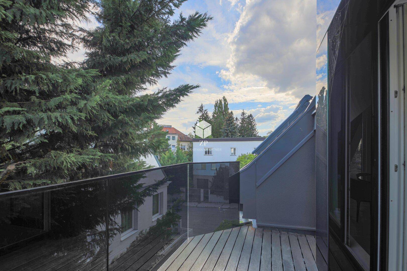 Geräumiger Balkon mit Glasbrüstung und Blick auf die umliegende grüne Landschaft.