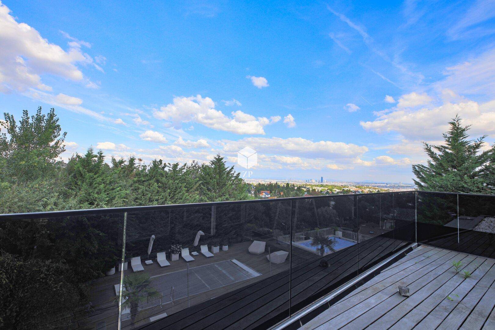 Balkon mit weitem Blick über eine Poollandschaft und die Stadt in der Ferne.