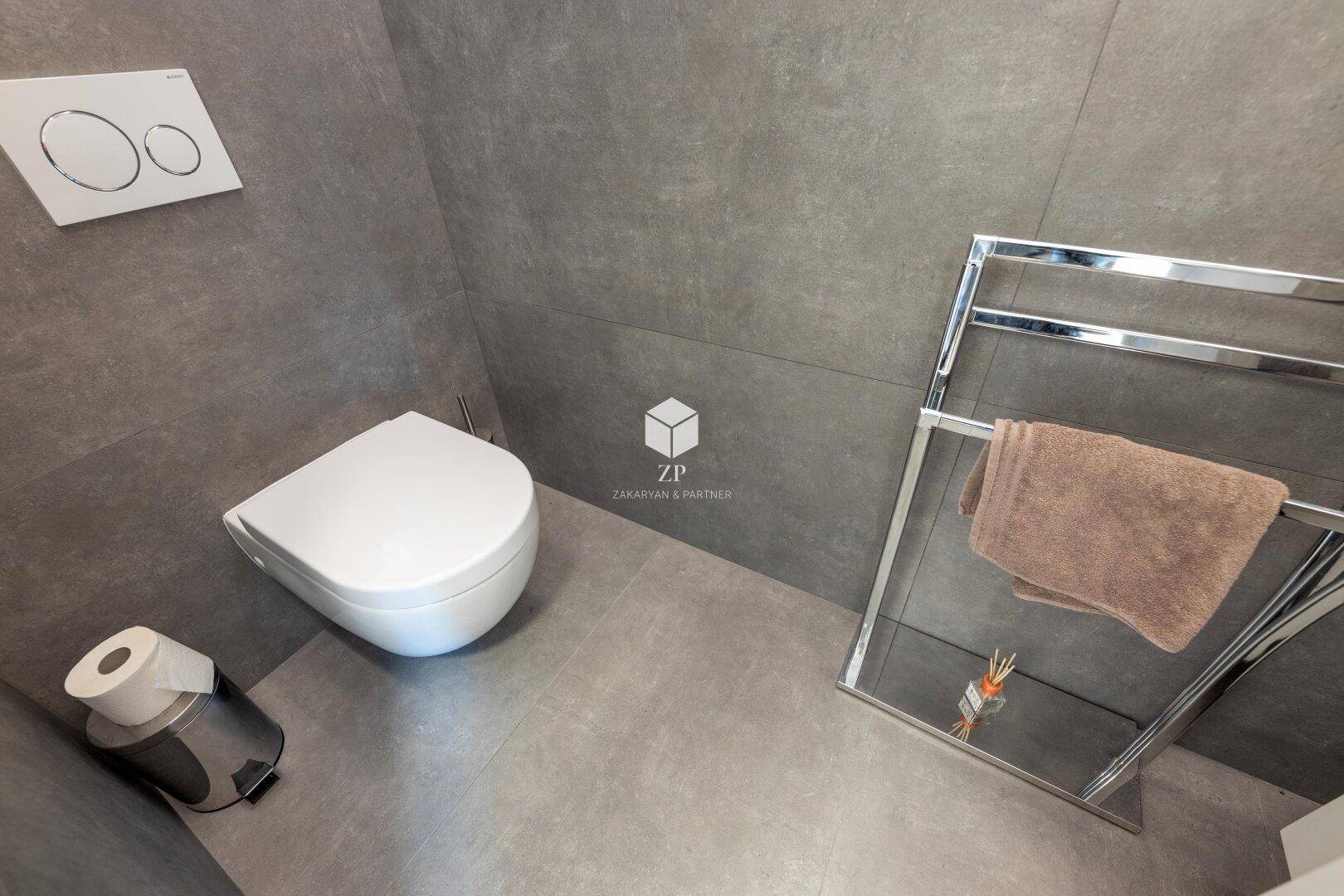 Modernes WC mit wandhängender Toilette und beheiztem Handtuchhalter.